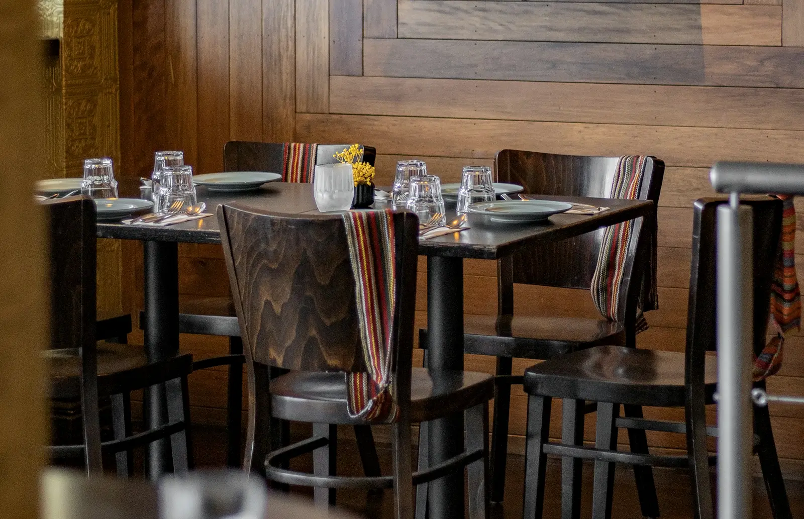 La sala della trattoria: tavoli in legno apparecchiati, runner a righe, luce calda